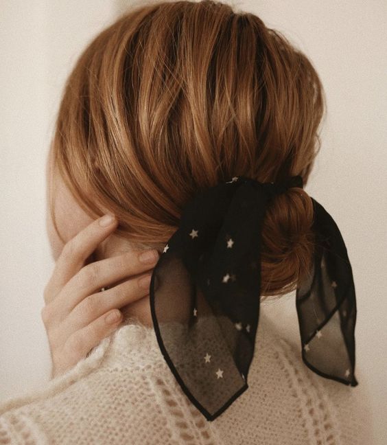 a low bun paired with a volumetric top, a black sheer scarf with gold stars for more elegance