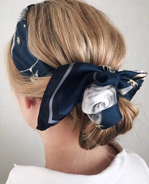 a low bun with a messy top and a navy printed scarf as a headband to accent the hairstyle