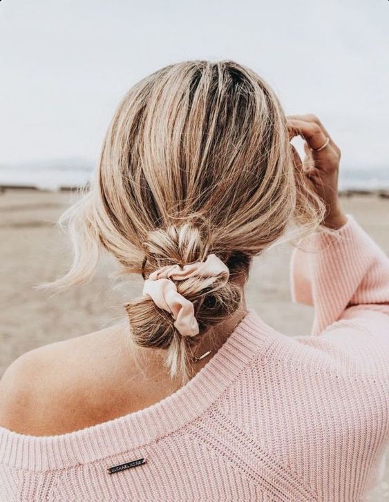 a low updo with a blush scrunchie interwoven in the hair is a dreamy and cool idea for medium and long hair