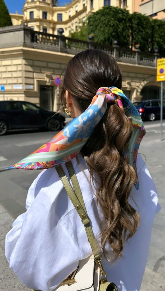 a low wavy ponytail with a volumetric top accented with a bright printed scarf is a cool idea to rock anytime