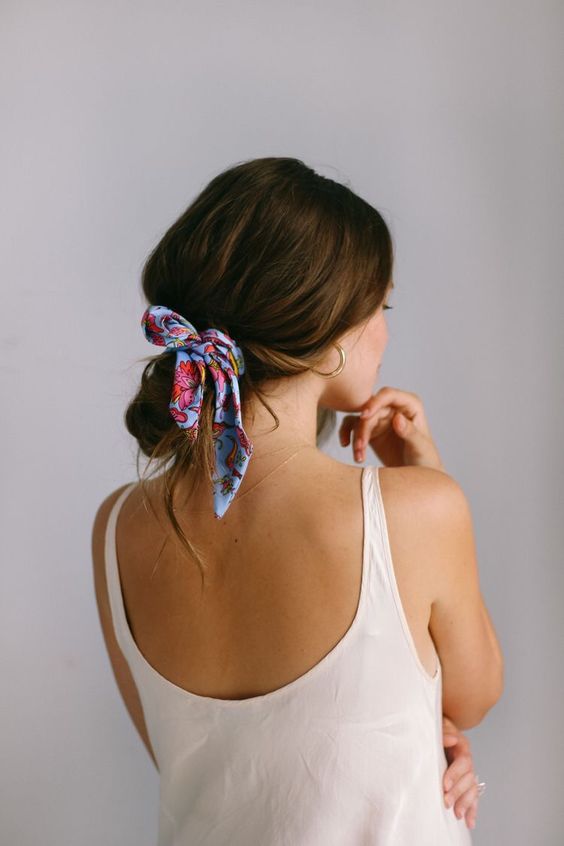 a messy low bun with a messy top and a colorful scarf as an accessory
