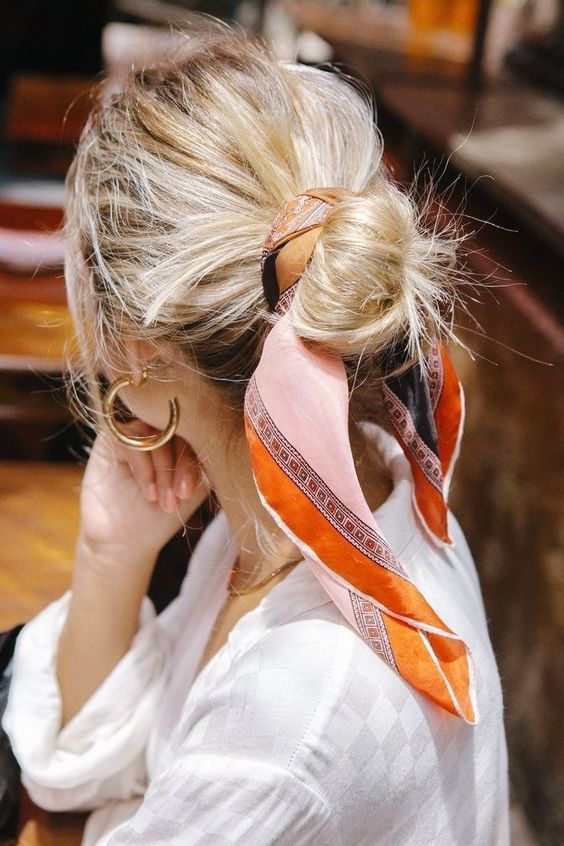 a messy midi bun with a pink and orange scarf as an accent, to add interest and color
