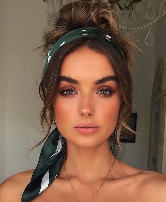 a messy top knot and messy hair on top, face-framing bangs and a green polka dot scarf used as a headband is a cool hairstyle