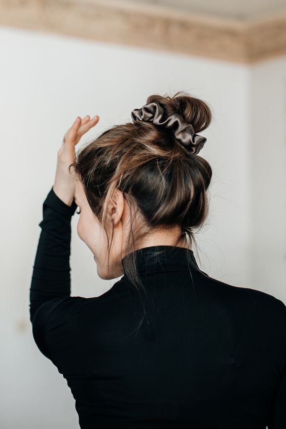 a messy top knot with a mesys top and a grey silk scrunchie is a cool hairstyle for every day