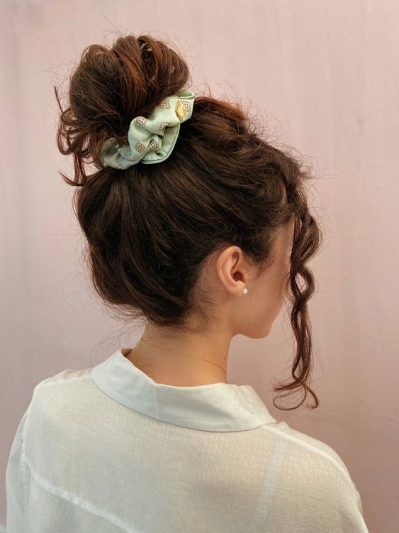 a messy wavy top knot with a wavy and volumetric top and wavy hair dow is a cool hairstyle