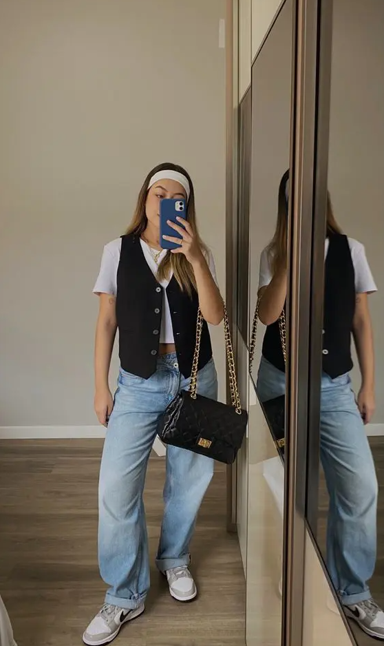 a relaxed and casual look with a white crop tee, a black vest, bleached jeans, sneakers and a black bag with chain
