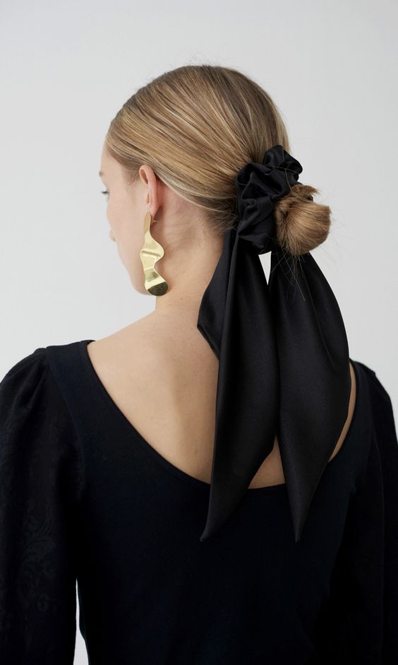 a sleek low bun with a sleek top and an elegant black silk scarf that matches the outfit and adds interest