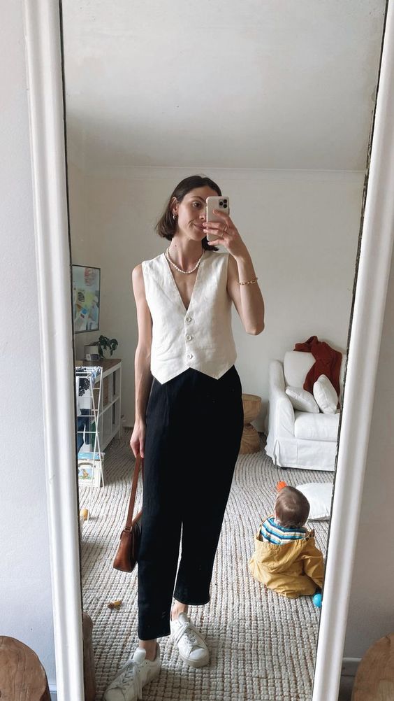 a smart casual summer look with a white linen vest, black cropped pants, white sneakers, a strand of pearls and a brown bag