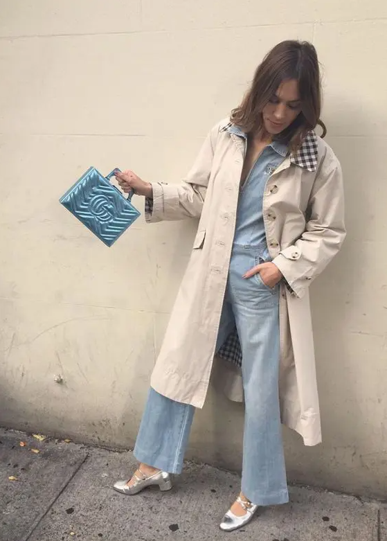 a spring outfit with a denim jumpsuit, a tan trench, silver Mary Jane shoes and a pastel blue bag