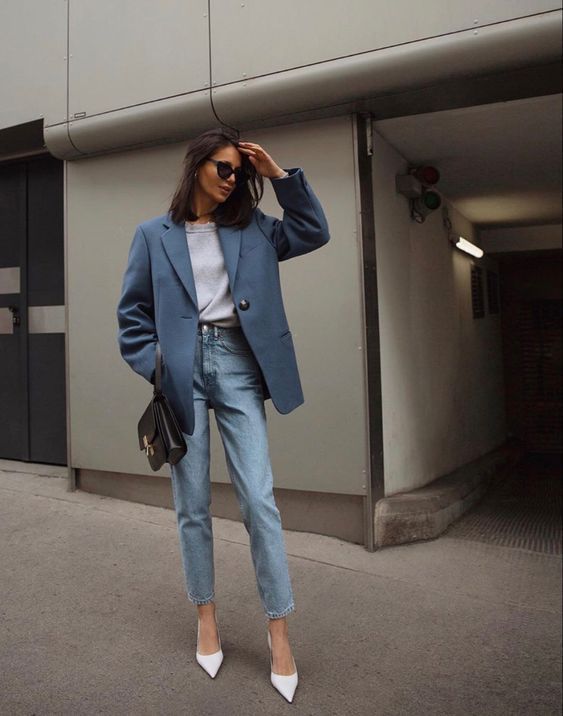 A spring work look with a grey t shirt, blue jeans, a blue oversized blazer, white shoes and a black bag