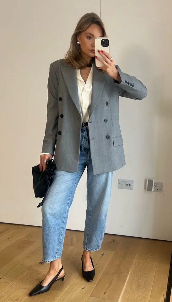 a spring work look with a neutral button down, a grey oversized blazer, blue jeans, black slingbacks and a black bag