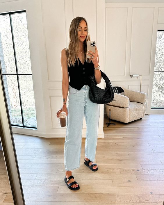 a summer every day outfit with a black waistcoat bleached cropped jeans black sandals and a black woven bag