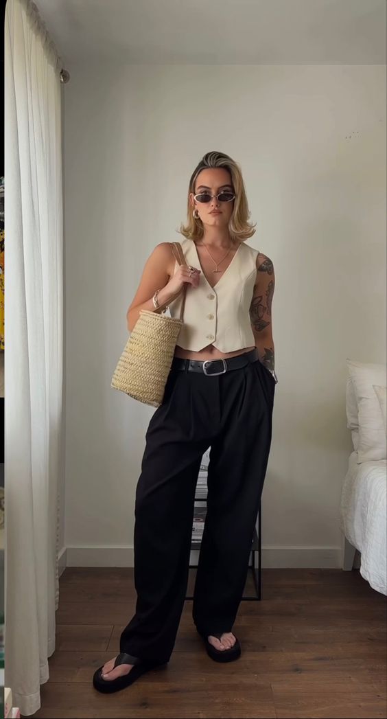 a summer outfit with a tan cropped waistcoat, black wideleg pants, black flipflops, a woven tote