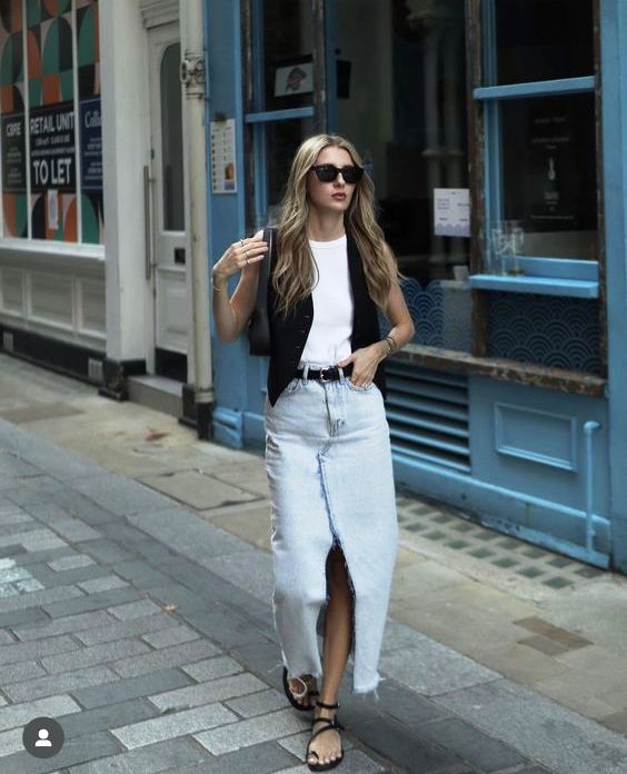 a summer outfit with a white top, a black waistcoat, a bleached denim midi, black sandals and a black bag