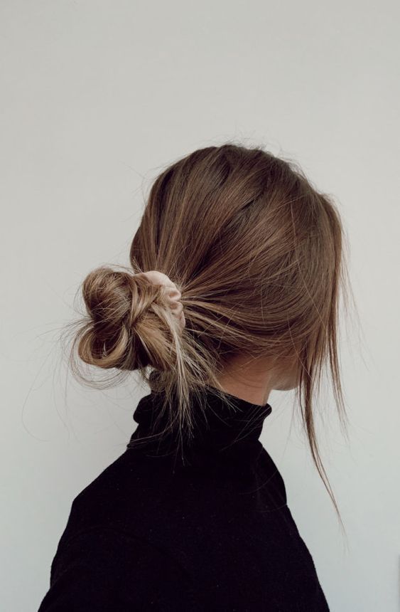a super messy low bun with a volumetric top and some face-framing hair plus a blush scrunchie is a hairstyle that can be made on the go