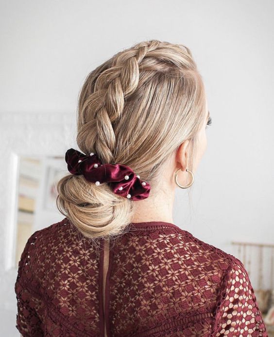 a top braid coming into a large low bun and a burgundy scrunchie with pearls are a cool and chic hairstyle