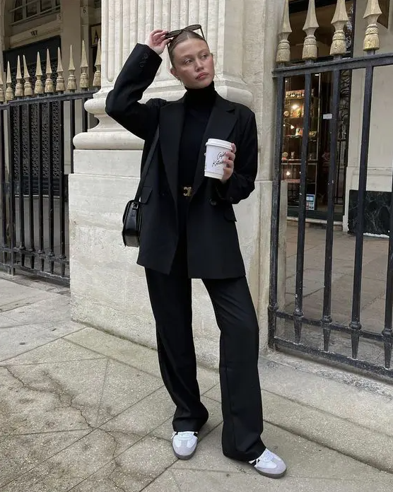 a total black look with a turtleneck, a pantsuit, a belt, a bag and white Adidas sneakers to refresh it