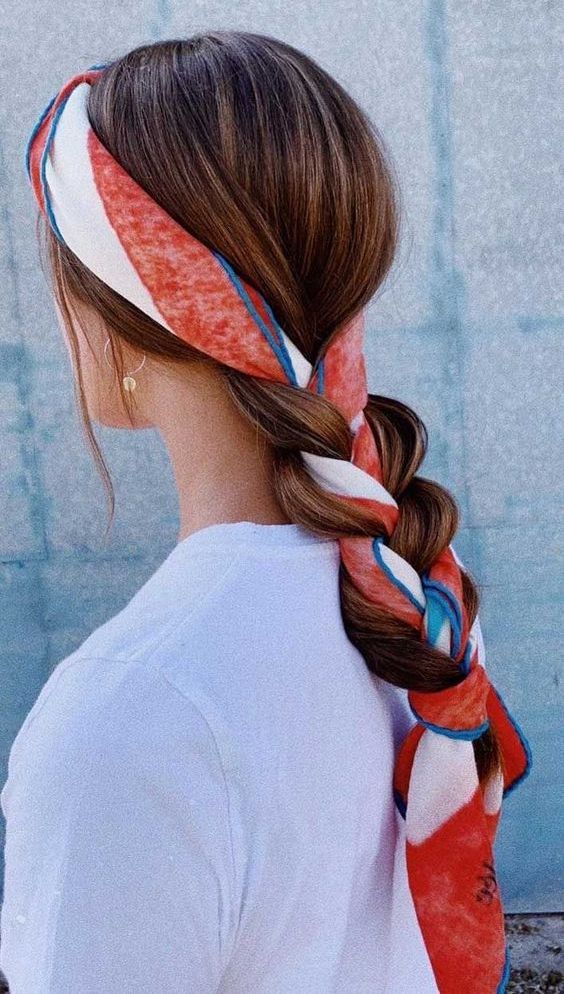 a volumetric low braid with a volumetric top and a bright scarf that is used both as a headband and part of the braid