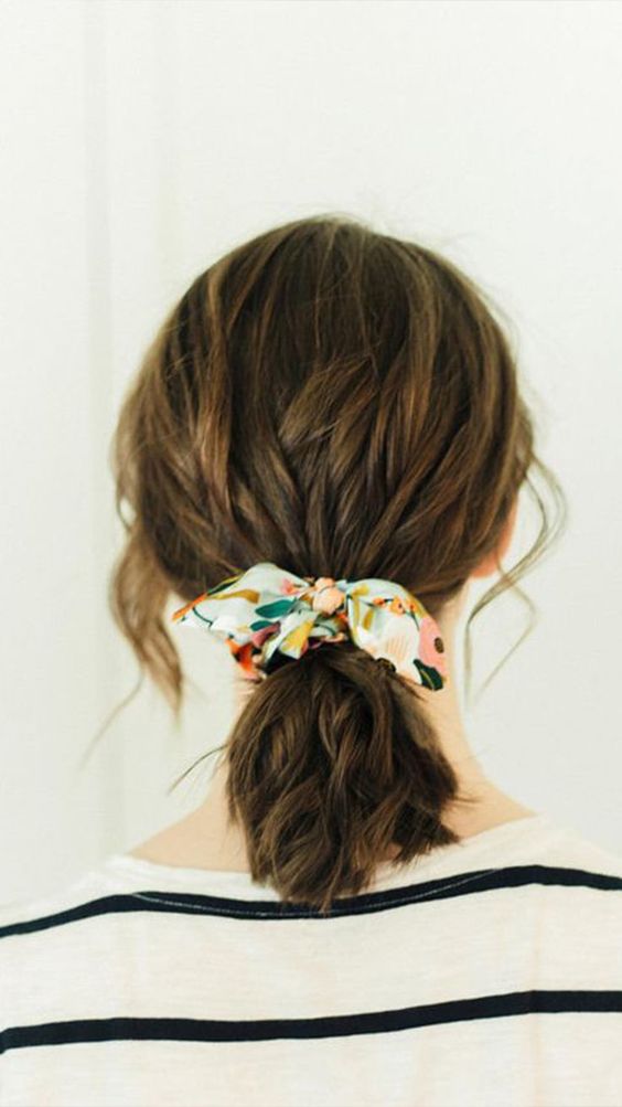 a wavy low ponytail with a messy top and a colorful scarf that forms a bow for an accent