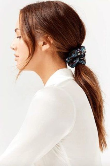 A wavy simple and quick to make low ponytail with face framing bangs and a colorful printed scrunchie for an accent