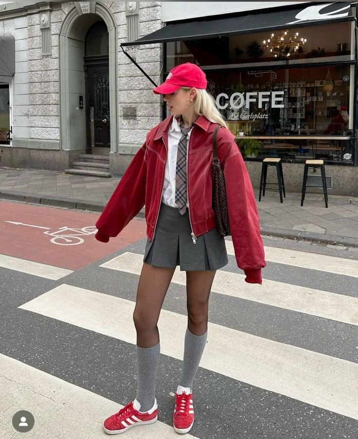 a white button down, a grey pleated mini skirt, a cherry red leather jacket, a tie, grey socks and a red cap and sneakers