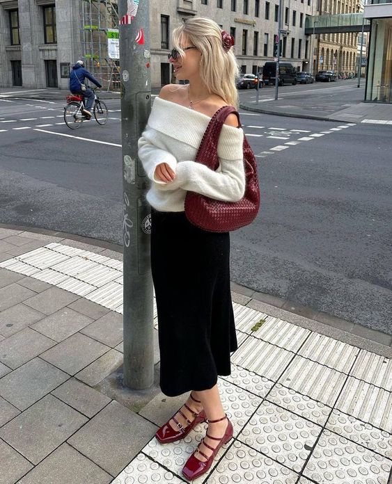 a white off the shoulder sweater, a black mini skirt, cherry red Mary Jane shoes and a matching woven hobo bag