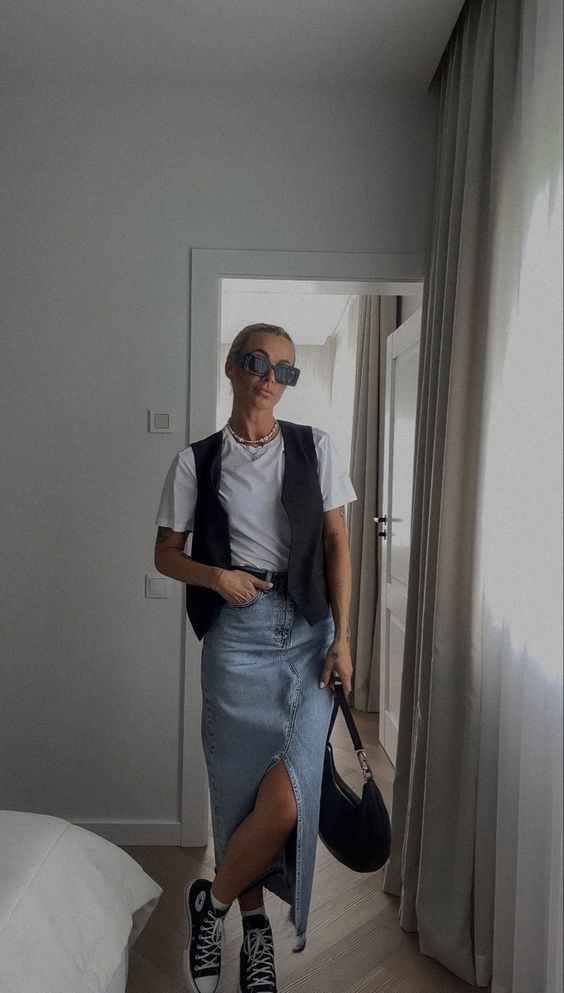 a white tee, a blue denim midi, a black waistcoat, black sneakers and a black bag for a cool summer look
