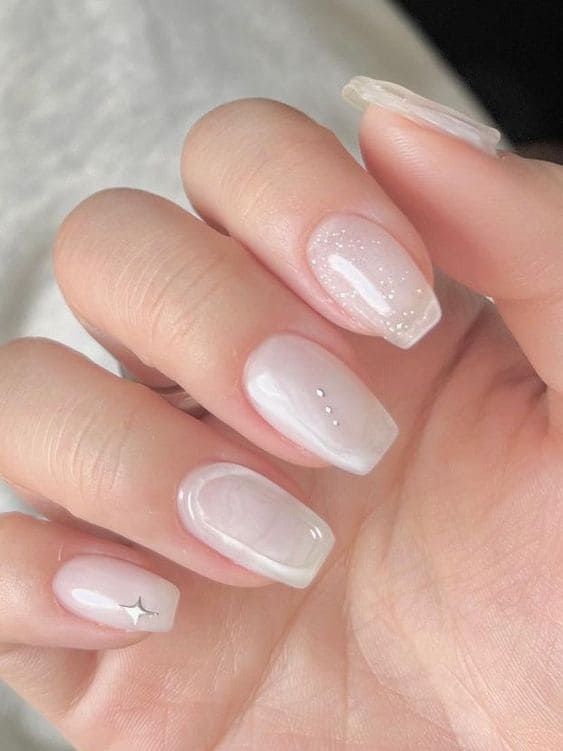 classy long milky nails with white beads, a star and glitter are very delicate, chic and beautiful