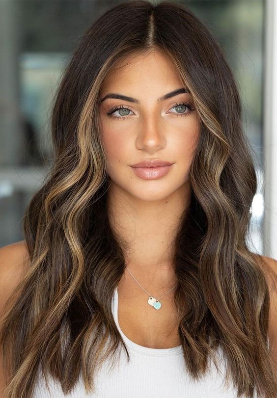 long dark brunette hair with golden blonde contouring and waves looks very summer-inspired and cool