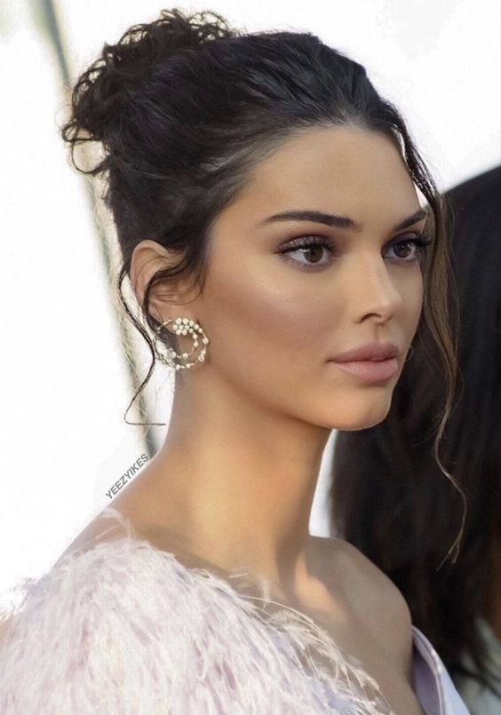 Kendall Jenner wearing a wavy messy top knot and a volume on top plus some locks down looks fab
