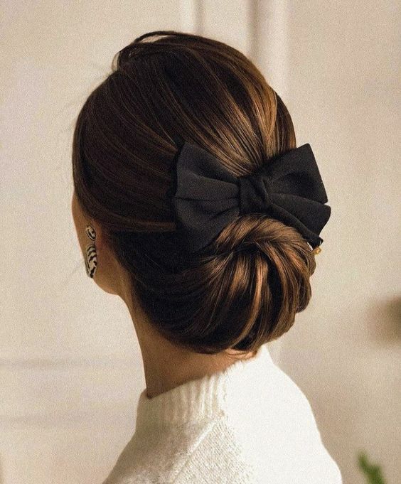 a beautiful and refined swirl low updo plus a volumetric top and a black bow for a special occasion or a party