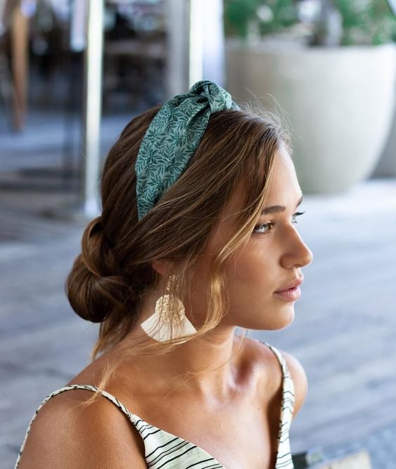 A beautiful hairstyle with a wrapped low updo and face framing hair plus a green printed headband for a vacation