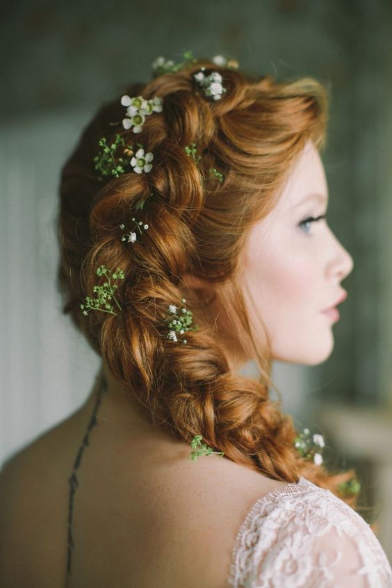 a beautiful side braid coming from the top of the head and accented with greenery and white blooms