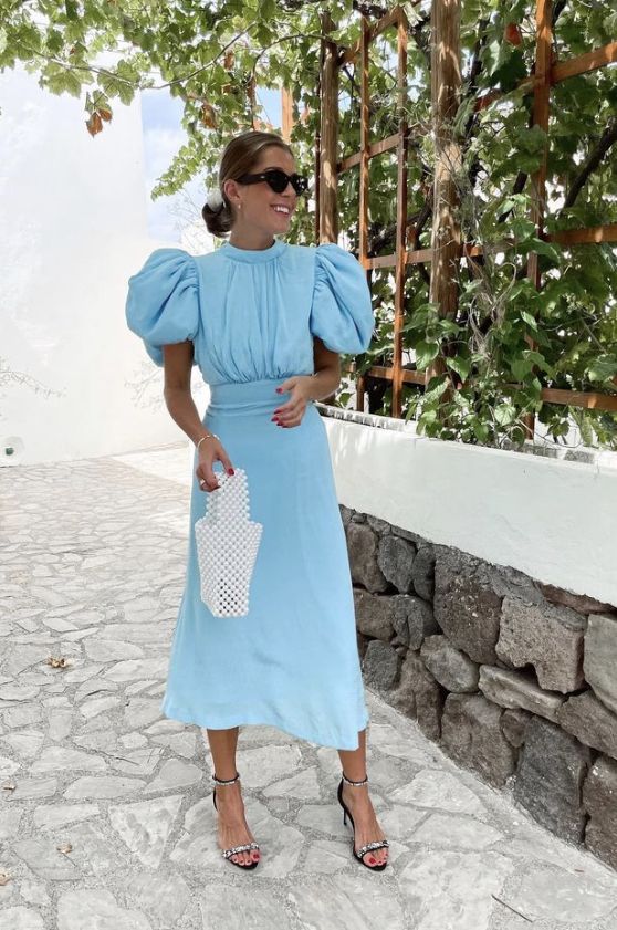 a blue midi dress with a high neckline, puff sleeves, black and silver shoes and a pearl bag for spring