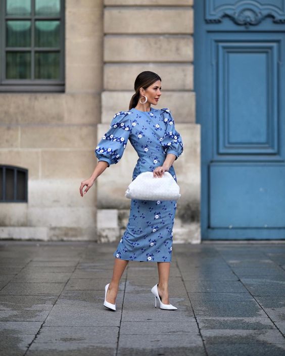 a blue midi fitting dress with puff sleeves and floral print, white shoes and a white bag for a spring bridal shower or wedding