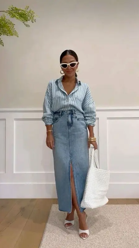 a blue striped shirt, a blue denim maxi skirt, white mules, a large white tote and chic bracelets