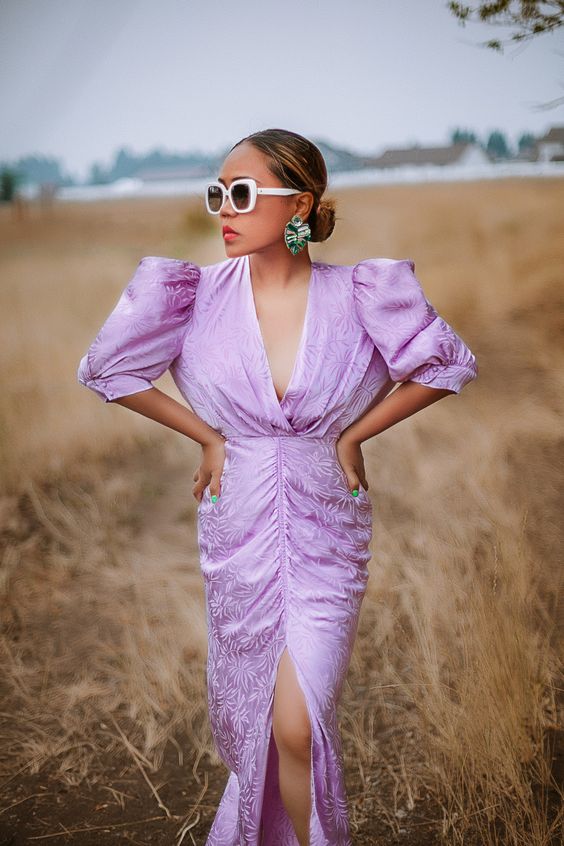 a bold and chic spring bridal shower look with a lilac printed maxi dress, a V-neckline, puff sleeves and a slit, statement earrings