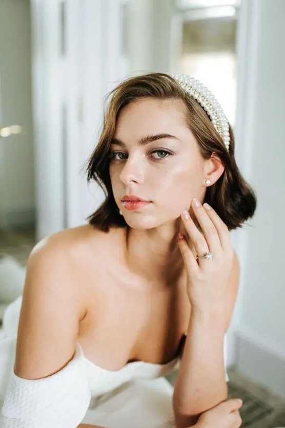 a brown wavy bob accented with a pearl headband is a very stylish and cool idea for a wedding