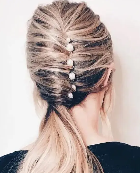 a catchy low ponytail with a twist and several pearl pins for a modern take on classics