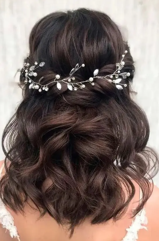 a charming twisted and wavy half updo with a volume on top accented with a pearl and rhinestone hair vine is a lovely idea