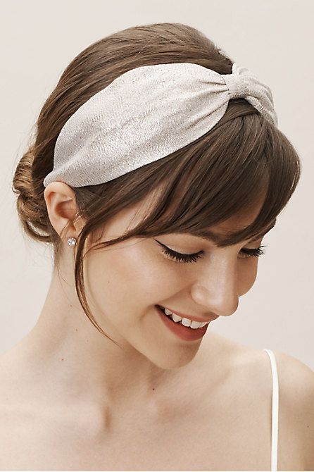 a chic hairdstyle with a low bun, layered bangs and a silver headband showing a bow is a lovely idea for a special occasion