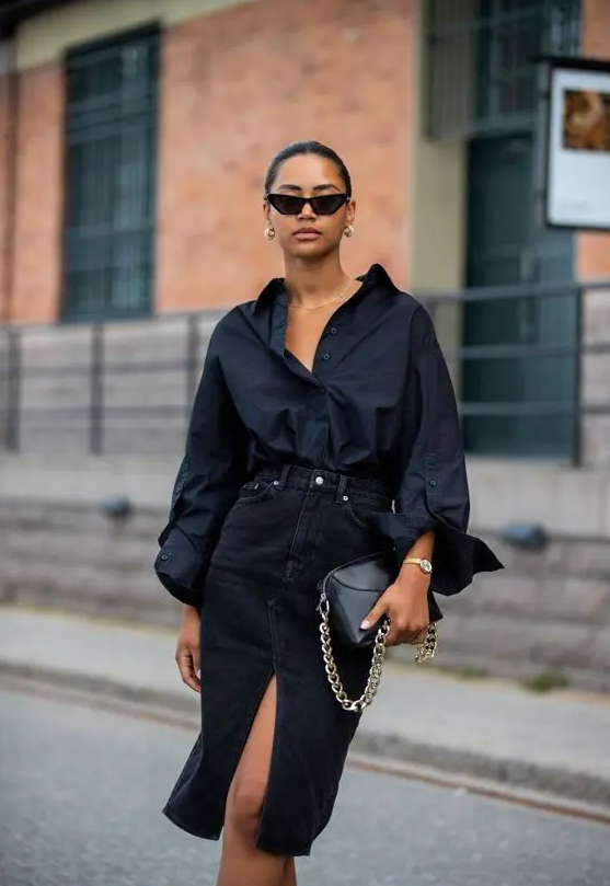 a chic night out look with an oversized black shirt, a black denim midi with a front slit, a black bag with gold chain