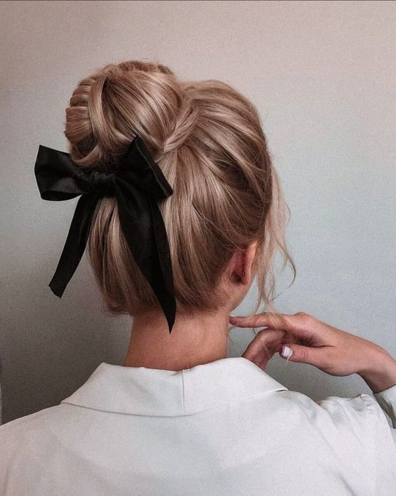 a complicated top knot wrapped and woven with a volumetric top and a black silk bow are a cool and refined idea for a party