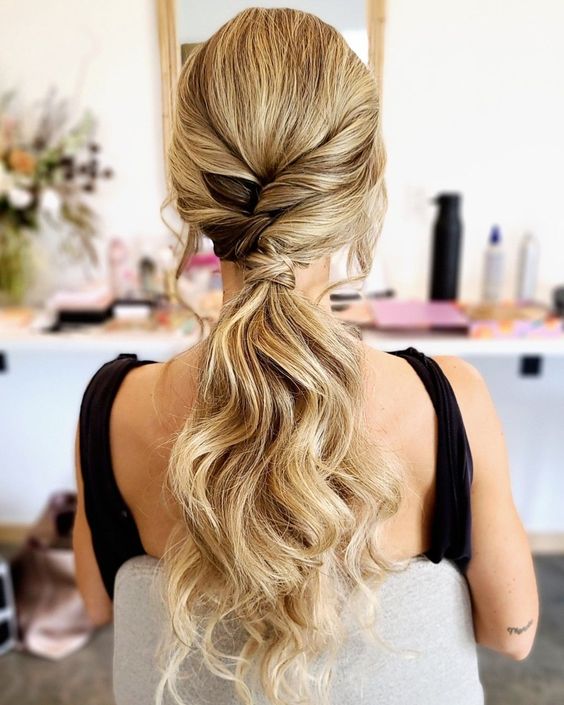 a cool low ponytail with twists and waves plus a volume on top is a chic idea for a modern bride