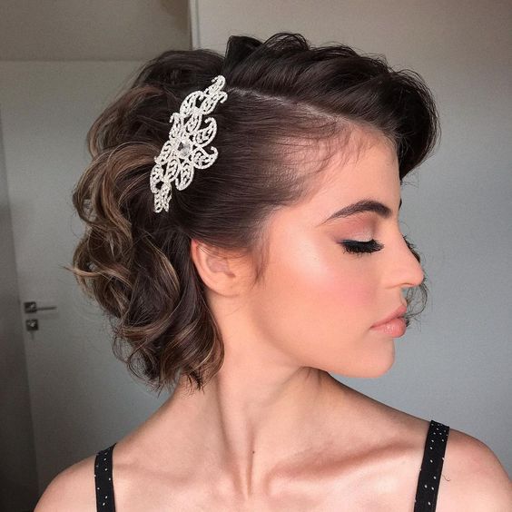 A curly bob accented with a lace like hair piece is a very chic and refined idea for a vintage bridal look
