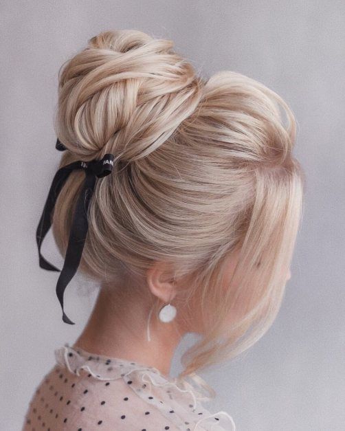 a cute wrapped top knot with a bump on top and face-framing hair plus a black ribbon bow for a trendy touch