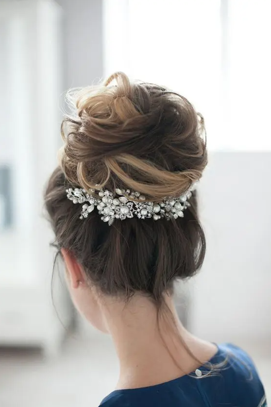 a dimensional messy top knot is accented with a large pearly hairpiece for a more refined feel