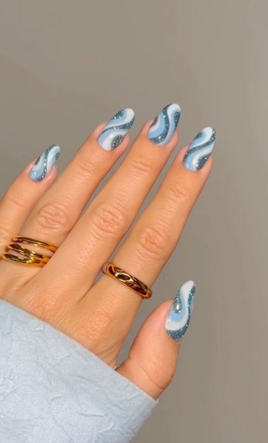 a gorgeous seaside inspired swirl manicure done in white, light blue and blue glitter swirls is amazing for a vacation