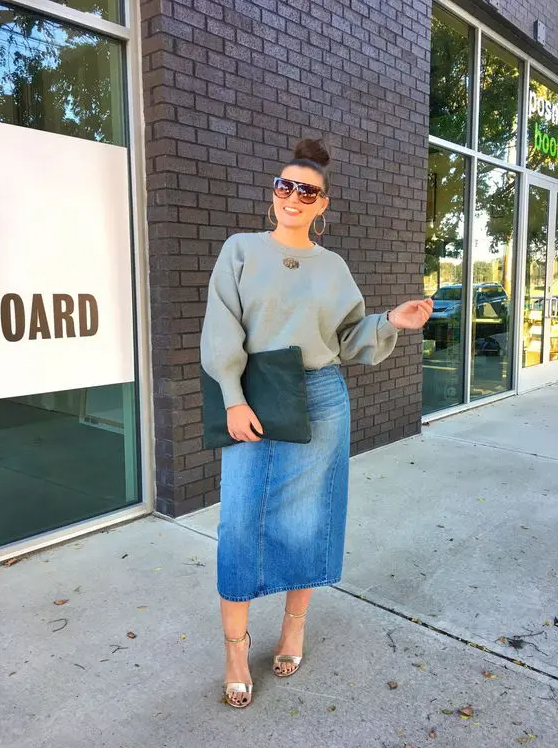 a grey sweatshirt, a blue denim midi skirt, silver shoes and a black clutch for a stylish and trendy outfit