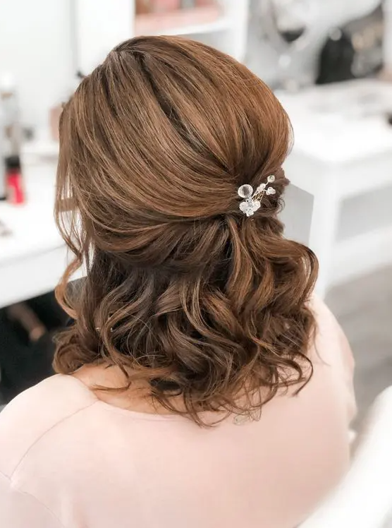 A half updo with a bump on top, waves down and face framing hair with a rhinestone hair pin is a cool solution